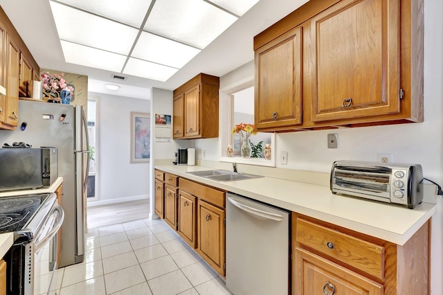 19819 Boca W Dr Unit 4033, Boca Raton, FL 33434 - kitchen with appliances with stainless steel finishes, light tile patterned floors, brown cabinetry, a sink, and light countertops