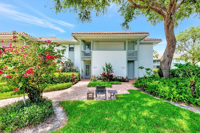 19819 Boca W Dr Unit 4033, Boca Raton, FL 33434 - back of house featuring stucco siding, a tiled roof, a lawn, and a balcony