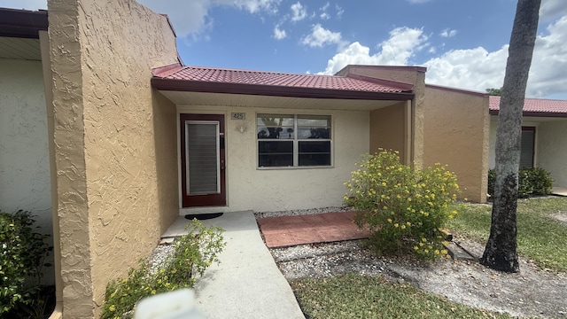 425 Lake Helen Dr, West Palm Beach, FL 33411 - view of exterior entry with stucco siding and a tiled roof