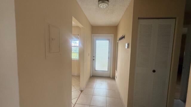 425 Lake Helen Dr, West Palm Beach, FL 33411 - entryway with a textured ceiling, light tile patterned floors, electric panel, and baseboards