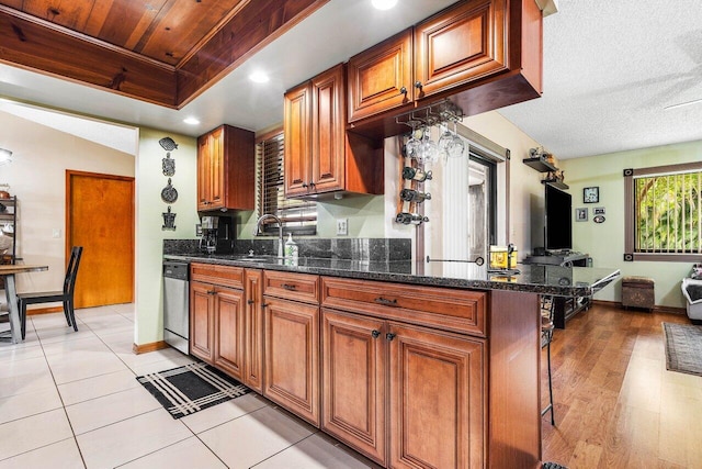 129 Parkwood Dr, Royal Palm Beach, FL 33411 - kitchen featuring dishwasher, brown cabinetry, a sink, dark stone counters, and a breakfast bar area