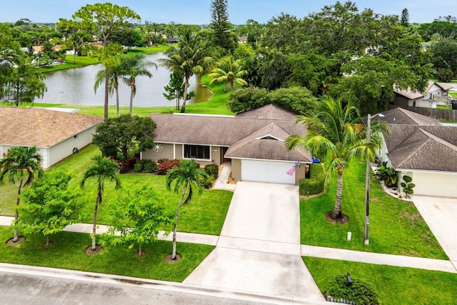 129 Parkwood Dr, Royal Palm Beach, FL 33411 - view of front of house featuring a water view, concrete driveway, a front lawn, and an attached garage