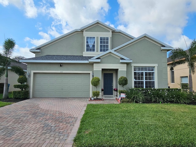 426 Cadiz Loop, Davenport, FL 33837 - traditional home featuring stucco siding, decorative driveway, a front yard, an attached garage, and a shingled roof