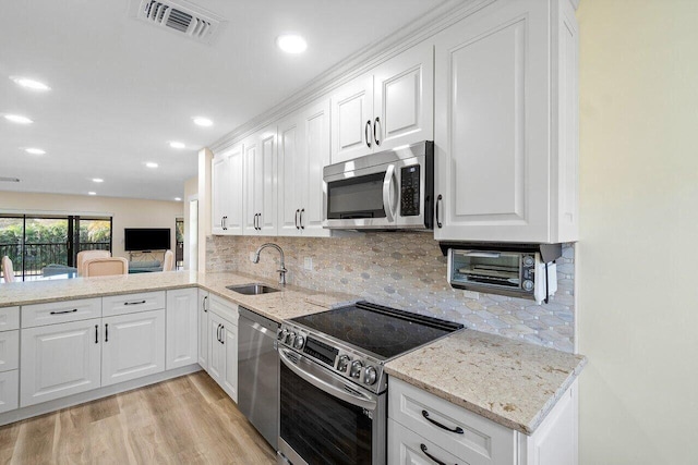 36 Stratford Ln Unit H, Boynton Beach, FL 33436 - kitchen featuring appliances with stainless steel finishes, white cabinetry, light wood-type flooring, decorative backsplash, and recessed lighting