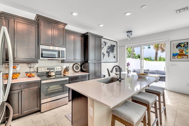 4340 Lago Dr, Deerfield Beach, FL 33064 - kitchen featuring stainless steel appliances, a sink, light tile patterned floors, a breakfast bar, and recessed lighting