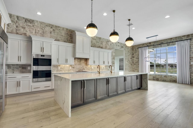 10032 Calabrese Trl, Jupiter, FL 33478 - kitchen with light countertops, light wood-type flooring, a spacious island, backsplash, and recessed lighting