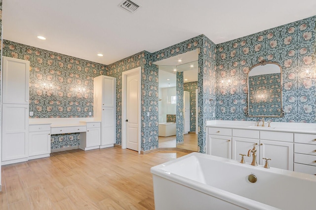 10032 Calabrese Trl, Jupiter, FL 33478 - full bath with wallpapered walls, a soaking tub, wood finished floors, vanity, and recessed lighting