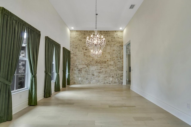 10032 Calabrese Trl, Jupiter, FL 33478 - unfurnished dining area with a chandelier, wood finished floors, healthy amount of natural light, brick wall, and baseboards