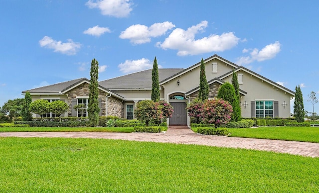 10032 Calabrese Trl, Jupiter, FL 33478 - view of front facade featuring stone siding, stucco siding, and a front yard