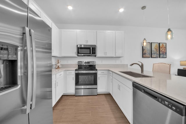 14517 Three Ponds Trl, Delray Beach, FL 33446 - kitchen featuring appliances with stainless steel finishes, a sink, white cabinets, pendant lighting, and light stone counters