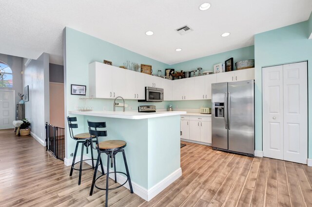 7989 Lakewood Cove Ct, Lake Worth, FL 33467 - kitchen featuring appliances with stainless steel finishes, light wood-type flooring, light countertops, a peninsula, and recessed lighting