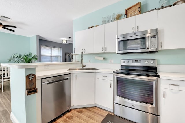 7989 Lakewood Cove Ct, Lake Worth, FL 33467 - kitchen featuring stainless steel appliances, a sink, light wood finished floors, and a peninsula