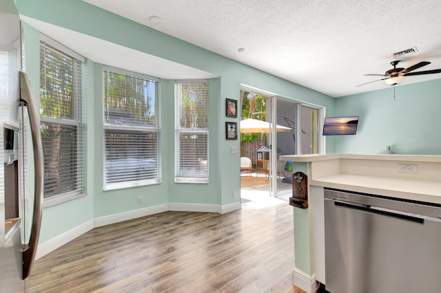 7989 Lakewood Cove Ct, Lake Worth, FL 33467 - kitchen featuring appliances with stainless steel finishes, light wood-style flooring, a ceiling fan, baseboards, and a textured ceiling