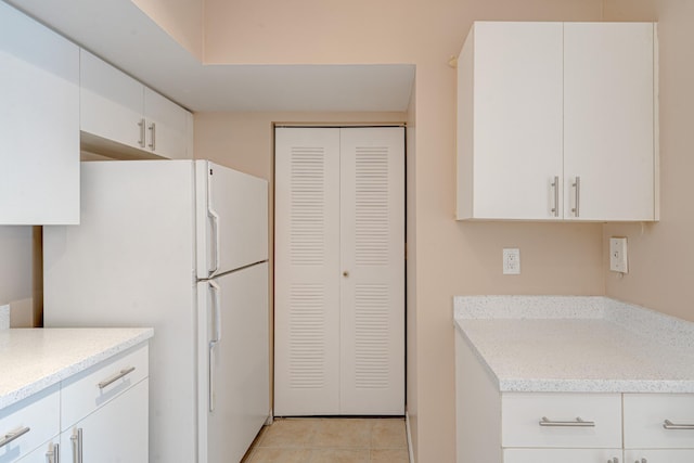 3870 Lyons Rd Unit 308-8, Coconut Creek, FL 33073 - kitchen with freestanding refrigerator, light tile patterned floors, white cabinetry, and light stone counters