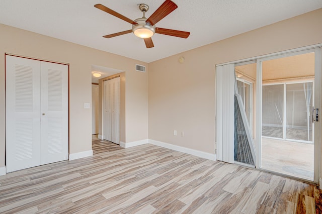 3870 Lyons Rd Unit 308-8, Coconut Creek, FL 33073 - unfurnished bedroom featuring access to exterior, light wood-style floors, two closets, baseboards, and a ceiling fan