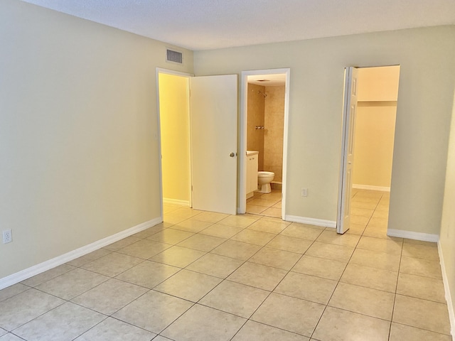 405 W Executive Center Dr Unit 208, West Palm Beach, FL 33401 - unfurnished bedroom featuring light tile patterned floors, a walk in closet, and baseboards