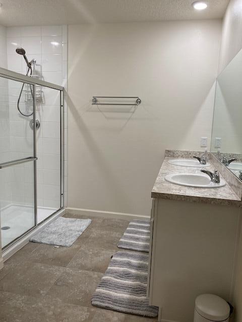 10789 SW Cremona Way, Port Saint Lucie, FL 34987 - bathroom with double vanity, a tile shower, and a textured ceiling