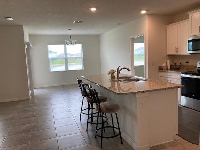 10789 SW Cremona Way, Port Saint Lucie, FL 34987 - kitchen with appliances with stainless steel finishes, plenty of natural light, an island with sink, light stone counters, and recessed lighting