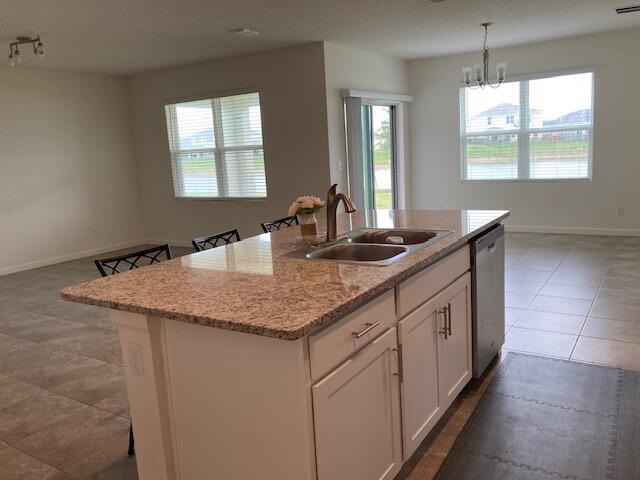 10789 SW Cremona Way, Port Saint Lucie, FL 34987 - kitchen featuring stainless steel dishwasher, white cabinets, an island with sink, and healthy amount of natural light