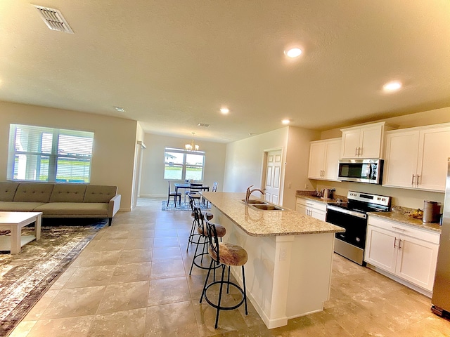 10789 SW Cremona Way, Port Saint Lucie, FL 34987 - kitchen with stainless steel appliances, a kitchen island with sink, recessed lighting, white cabinets, and a kitchen bar