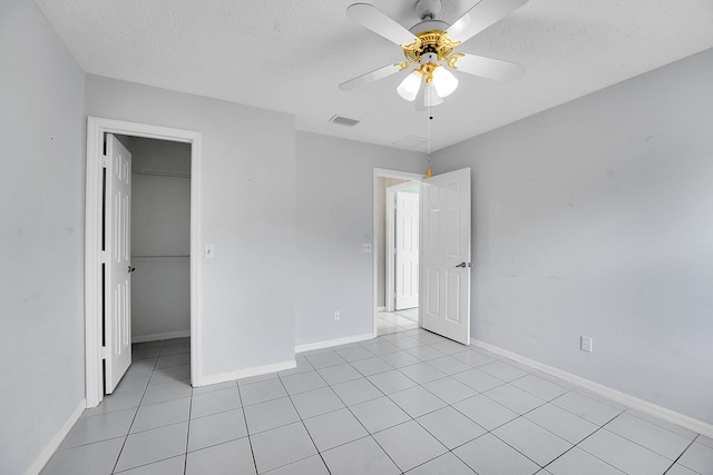654 SW Kayak Ave, Port Saint Lucie, FL 34953 - unfurnished bedroom featuring light tile patterned flooring, a textured ceiling, a spacious closet, ceiling fan, and baseboards
