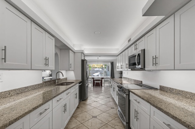 2476 S Florida Mango Rd, West Palm Beach, FL 33406 - kitchen featuring appliances with stainless steel finishes, a sink, light tile patterned flooring, a chandelier, and light stone countertops