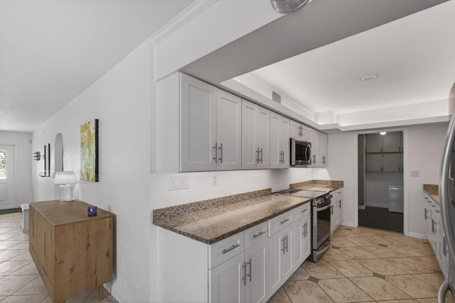2476 S Florida Mango Rd, West Palm Beach, FL 33406 - kitchen with appliances with stainless steel finishes, light tile patterned flooring, white cabinets, dark stone counters, and baseboards