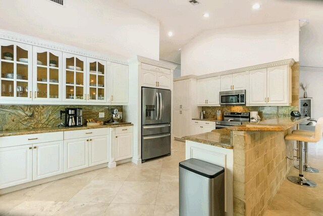 9823 NE Sun Pointe Dr, Boynton Beach, FL 33437 - kitchen featuring appliances with stainless steel finishes, glass insert cabinets, tasteful backsplash, a breakfast bar, and a peninsula