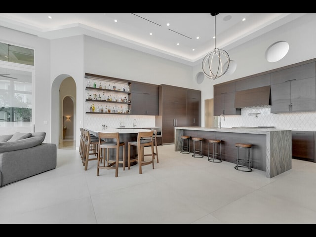12990 Marsh Lndg, Palm Beach Gardens, FL 33418 - dining room featuring arched walkways, a high ceiling, light tile patterned floors, bar area, and recessed lighting