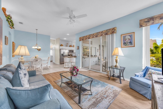 3592 SW Rosser Blvd, Port Saint Lucie, FL 34953 - living room with a ceiling fan, light wood-style flooring, a chandelier, and baseboards