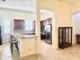 344 NW Stratford Ln, Port Saint Lucie, FL 34983 - kitchen with stainless steel appliances, arched walkways, a breakfast bar, and healthy amount of natural light