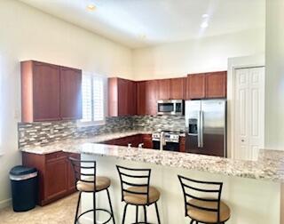 344 NW Stratford Ln, Port Saint Lucie, FL 34983 - kitchen featuring appliances with stainless steel finishes, a breakfast bar area, backsplash, and a peninsula