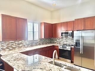 344 NW Stratford Ln, Port Saint Lucie, FL 34983 - kitchen with appliances with stainless steel finishes, light stone countertops, decorative backsplash, and a peninsula