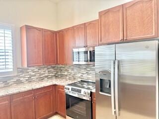 344 NW Stratford Ln, Port Saint Lucie, FL 34983 - kitchen with appliances with stainless steel finishes, plenty of natural light, tasteful backsplash, and light stone countertops
