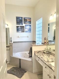 344 NW Stratford Ln, Port Saint Lucie, FL 34983 - bathroom featuring a jetted tub, vanity, and tile patterned flooring