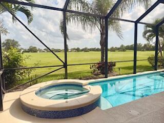 344 NW Stratford Ln, Port Saint Lucie, FL 34983 - view of swimming pool with glass enclosure, a pool with connected hot tub, and view of golf course