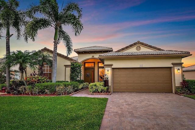 1415 SE Legacy Cove Cir, Stuart, FL 34997 - mediterranean / spanish home with stucco siding, an attached garage, decorative driveway, a lawn, and a tile roof