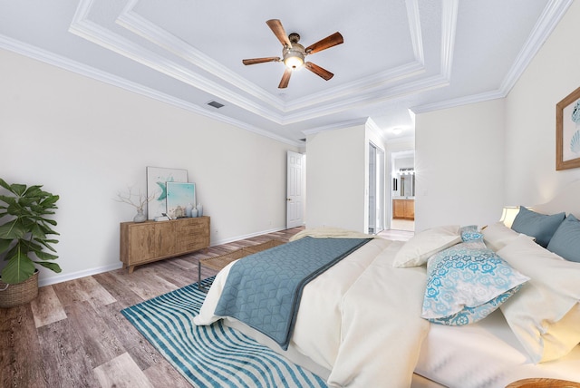 1415 SE Legacy Cove Cir, Stuart, FL 34997 - bedroom with a raised ceiling, wood finished floors, ornamental molding, connected bathroom, and ceiling fan