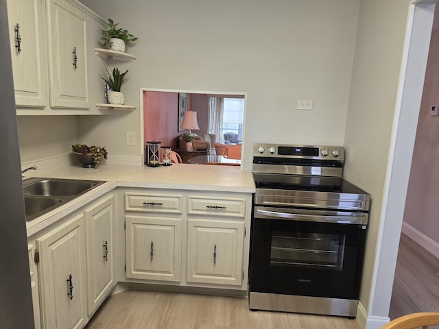 143 Lake Barbara Dr, West Palm Beach, FL 33411 - kitchen featuring stainless steel electric range oven, a sink, open shelves, light countertops, and light wood-style flooring