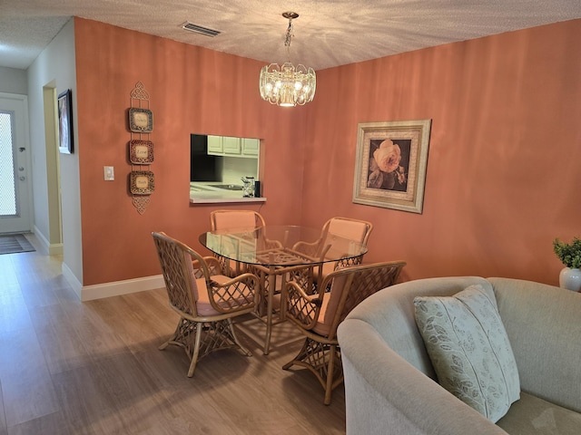 143 Lake Barbara Dr, West Palm Beach, FL 33411 - dining area featuring wood finished floors, a chandelier, baseboards, and a textured ceiling