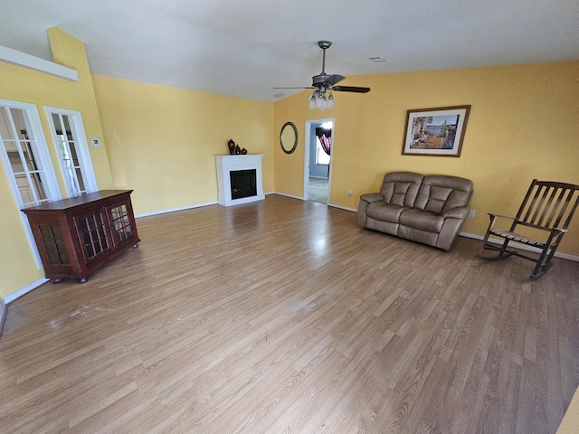 3817 SW Cheribon St, Port Saint Lucie, FL 34953 - unfurnished living room with wood finished floors, a ceiling fan, baseboards, and a fireplace