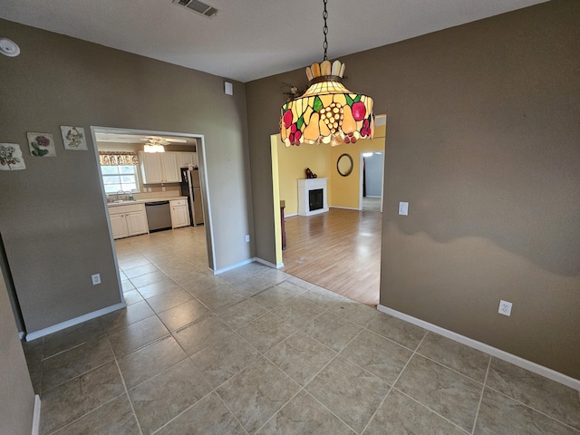 3817 SW Cheribon St, Port Saint Lucie, FL 34953 - unfurnished dining area featuring light tile patterned flooring, baseboards, ceiling fan, a sink, and a fireplace