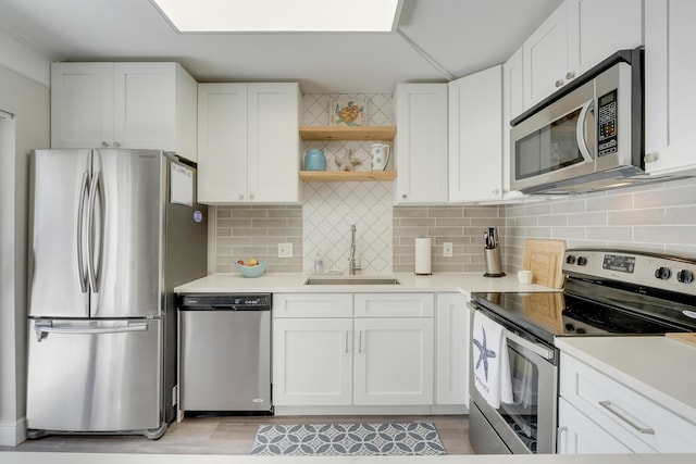 3900 County Line Rd Unit 4C, Tequesta, FL 33469 - kitchen featuring stainless steel appliances, a sink, open shelves, white cabinetry, and light countertops