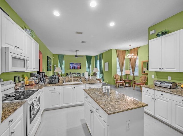 1081 SW Jacqueline Ave, Port Saint Lucie, FL 34953 - kitchen featuring white appliances, a center island, a chandelier, white cabinetry, and light stone counters