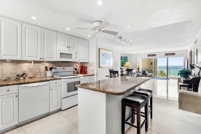 3101 S Ocean Blvd Unit 706, Highland Beach, FL 33487 - kitchen featuring white appliances, a breakfast bar, backsplash, dark stone countertops, and white cabinets