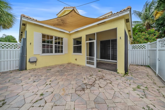 5554 Boynton Gardens Dr, Boynton Beach, FL 33437 - back of property featuring stucco siding, a patio, a gate, a tile roof, and a sunroom