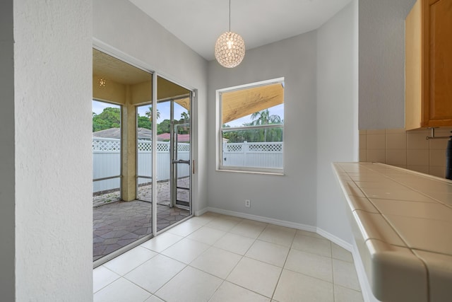 5554 Boynton Gardens Dr, Boynton Beach, FL 33437 - unfurnished dining area featuring light tile patterned floors, a chandelier, and baseboards