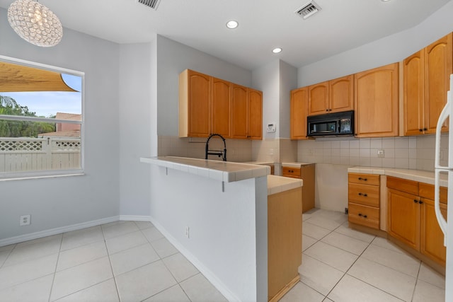 5554 Boynton Gardens Dr, Boynton Beach, FL 33437 - kitchen with black microwave, a peninsula, backsplash, light tile patterned floors, and recessed lighting