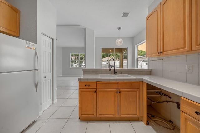 5554 Boynton Gardens Dr, Boynton Beach, FL 33437 - kitchen with freestanding refrigerator, a sink, a peninsula, tasteful backsplash, and healthy amount of natural light