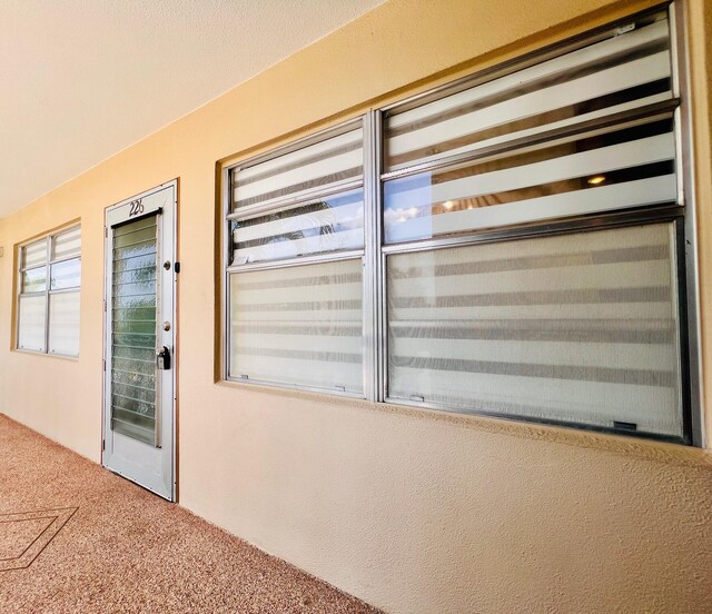 226 Wellington Unit G, West Palm Beach, FL 33417 - view of exterior entry with stucco siding and a garage